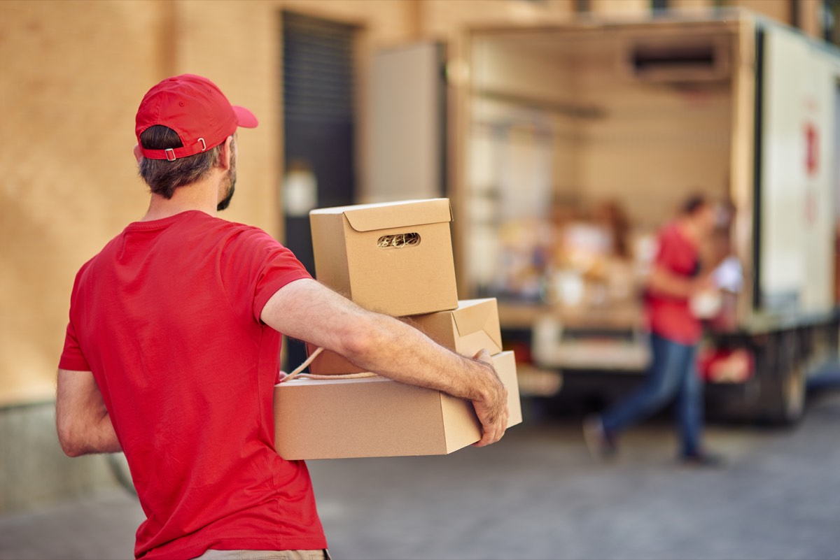 Courier in uniform standing at a warehouse with parcels